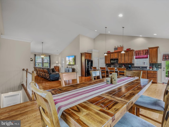 dining room with high vaulted ceiling, light wood-type flooring, and recessed lighting