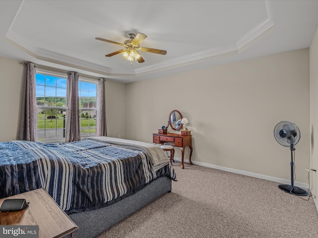 carpeted bedroom with a raised ceiling, crown molding, baseboards, and ceiling fan