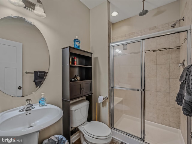 bathroom featuring a sink, a stall shower, and toilet