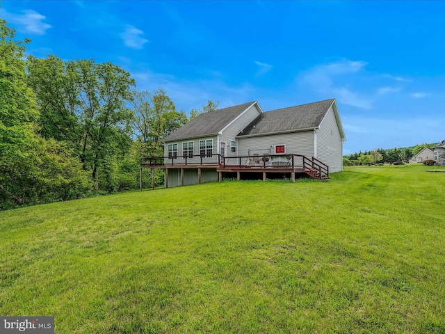 back of property with a wooden deck, a lawn, and a shingled roof