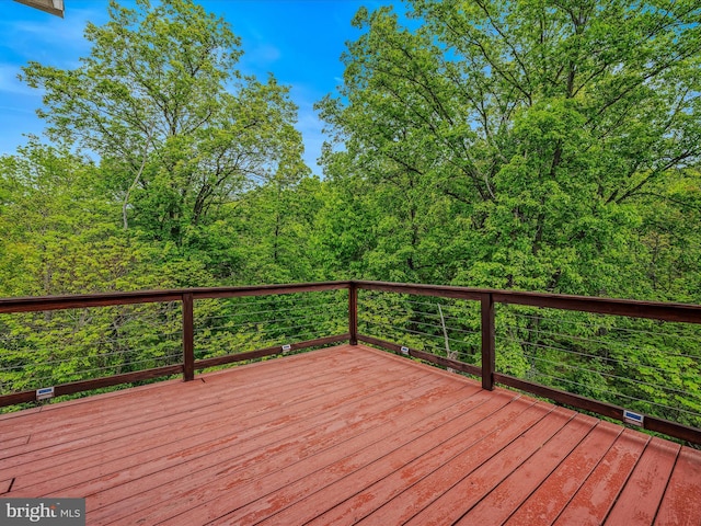 wooden terrace featuring a view of trees