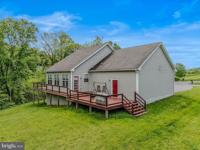 rear view of property with a deck, a yard, and roof with shingles