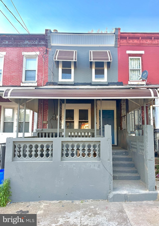 townhome / multi-family property with a porch and brick siding