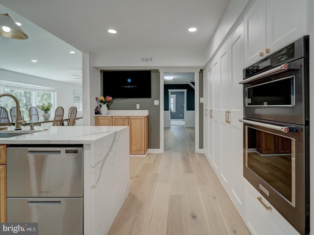 1782 Shaftsbury Ave, Crofton, MD 21114 - kitchen featuring double oven, a sink, dishwasher, light wood-type flooring, and light stone countertops