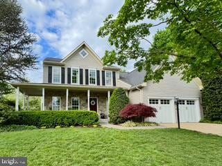 colonial-style house featuring concrete driveway, a garage, and a front lawn