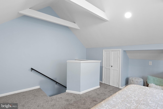 carpeted bedroom with a closet, baseboards, and vaulted ceiling with beams