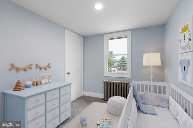 carpeted bedroom with baseboards, radiator, and a crib