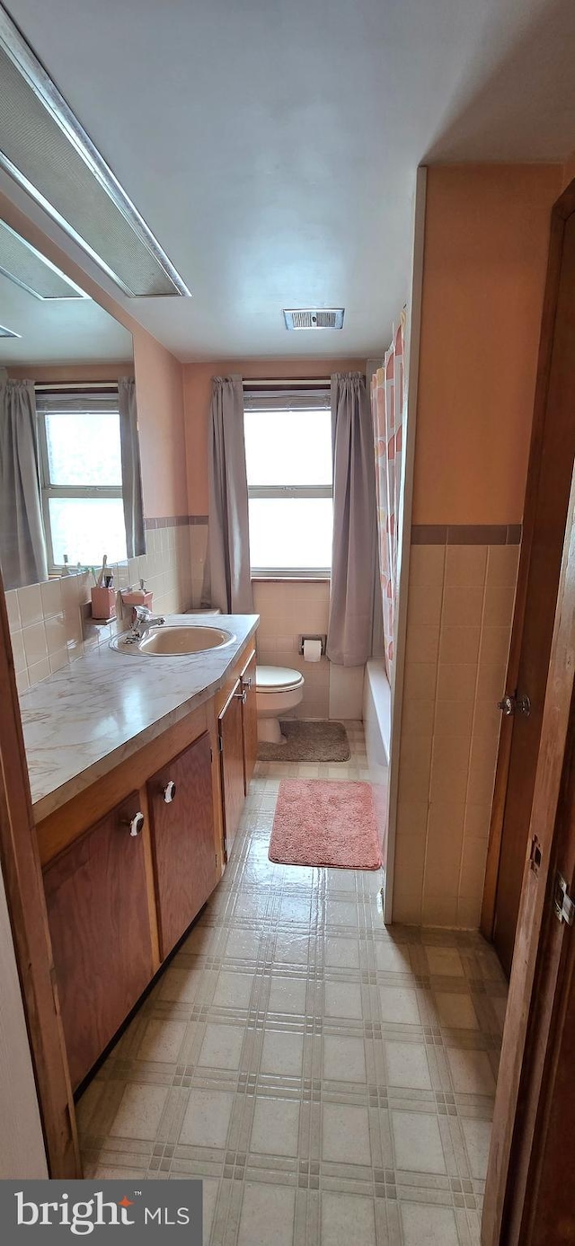 8074 Molly Pitcher Hwy, Shippensburg, PA 17257 - bathroom with plenty of natural light, toilet, vanity, shower / bath combination with curtain, and a wainscoted wall