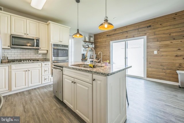 31 Walters Way, Dover, DE 19904 - kitchen featuring stainless steel appliances, light wood-style flooring, decorative backsplash, wooden walls, and a sink