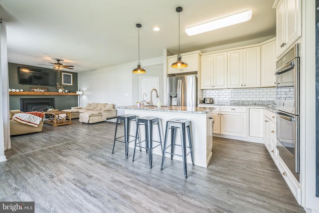 31 Walters Way, Dover, DE 19904 - kitchen featuring stainless steel appliances, decorative backsplash, a ceiling fan, light stone countertops, and a kitchen bar