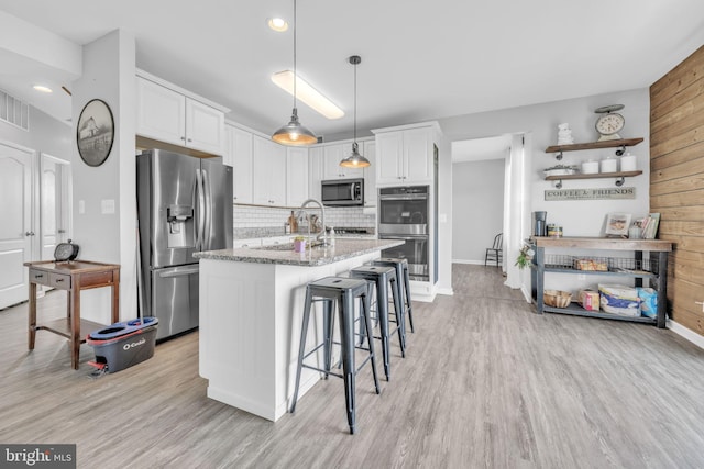 31 Walters Way, Dover, DE 19904 - kitchen featuring stainless steel appliances, light wood-style floors, decorative backsplash, white cabinetry, and wooden walls