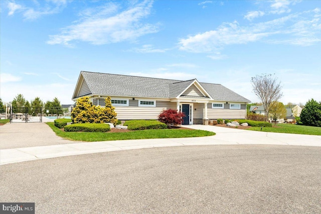 view of front of home with a gate, roof with shingles, fence, and driveway