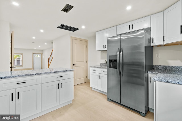 kitchen with light wood-style floors, light stone countertops, stainless steel refrigerator with ice dispenser, and white cabinetry