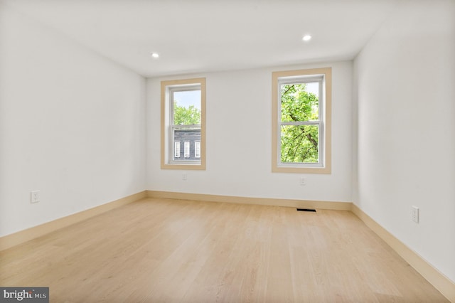 unfurnished room with recessed lighting, visible vents, a healthy amount of sunlight, and wood finished floors