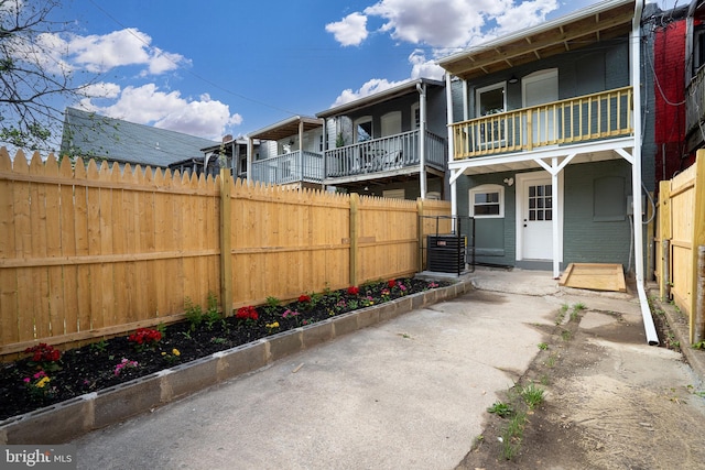 exterior space with brick siding, central AC, fence, and a balcony