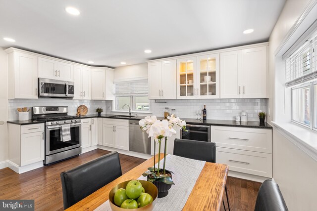kitchen featuring tasteful backsplash, appliances with stainless steel finishes, white cabinets, and glass insert cabinets
