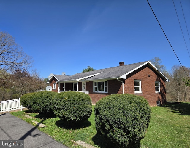 ranch-style home with brick siding, a chimney, and a front yard