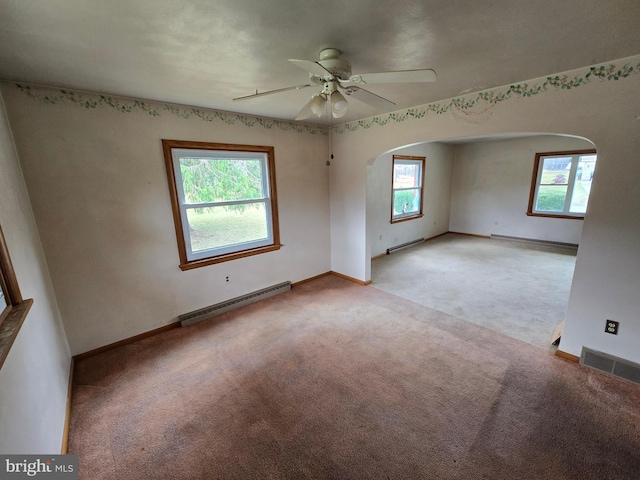 unfurnished room featuring baseboard heating, arched walkways, ceiling fan, and light carpet