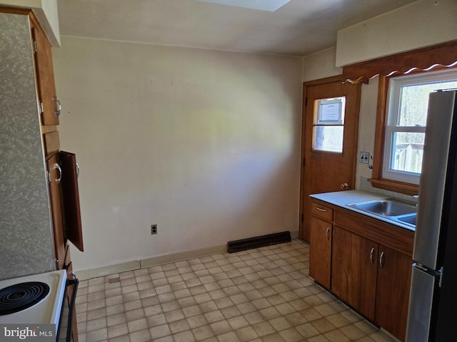 kitchen featuring electric range, a sink, light countertops, freestanding refrigerator, and visible vents