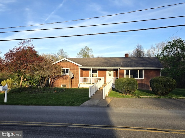 single story home with a porch, brick siding, a chimney, and a front yard