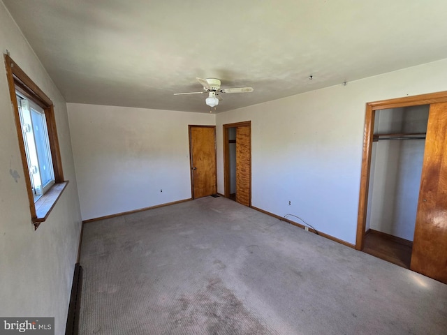 unfurnished bedroom featuring baseboards, carpet flooring, ceiling fan, and two closets