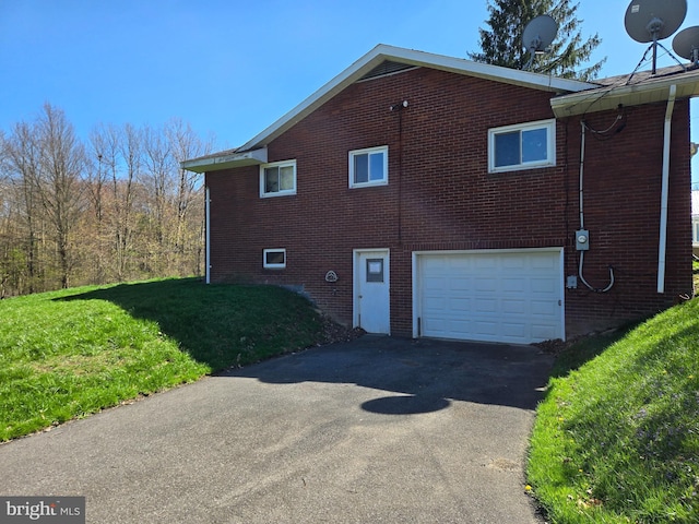 view of property exterior with an attached garage, aphalt driveway, a yard, and brick siding