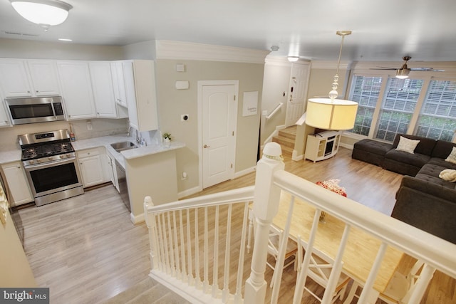 2350 Merseyside Dr, Woodbridge, VA 22191 - kitchen with stainless steel appliances, a sink, light wood-style flooring, light countertops, and crown molding