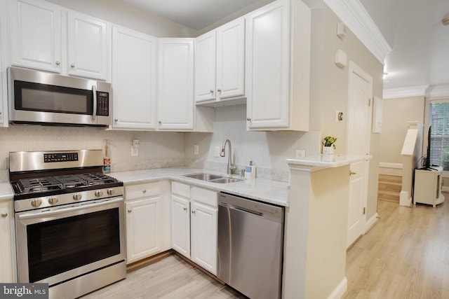 2350 Merseyside Dr, Woodbridge, VA 22191 - kitchen featuring appliances with stainless steel finishes, a sink, light wood-type flooring, white cabinets, and decorative backsplash