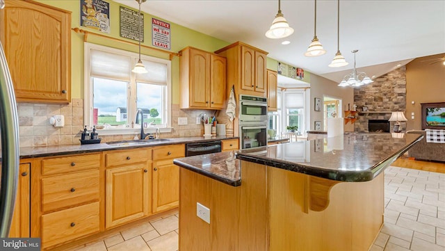 kitchen with a sink, stainless steel double oven, healthy amount of natural light, a center island, and vaulted ceiling