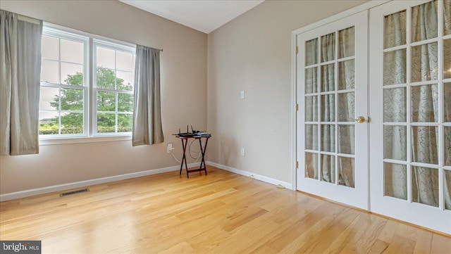 unfurnished room with wood finished floors, baseboards, and french doors