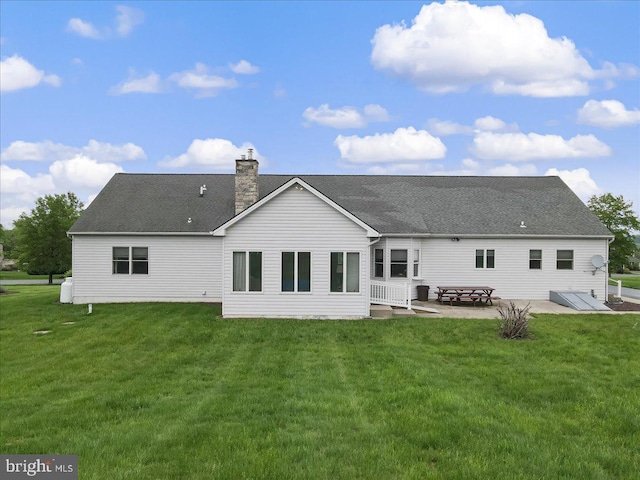 back of property with a patio, a yard, a chimney, and roof with shingles
