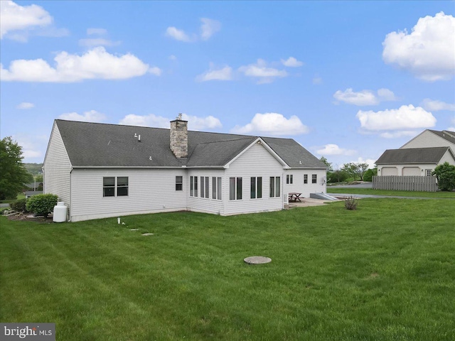 back of house with a lawn, a chimney, and a shingled roof