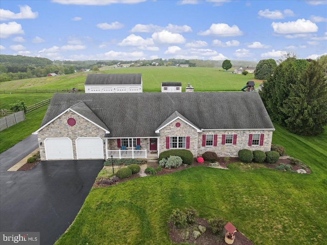 view of front of home featuring stone siding, an attached garage, asphalt driveway, and a rural view