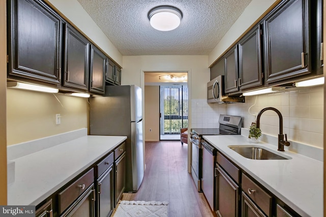 5300 Holmes Run Pkwy Unit 407, Alexandria, VA 22304 - kitchen featuring a sink, appliances with stainless steel finishes, light countertops, light wood-style flooring, and a textured ceiling