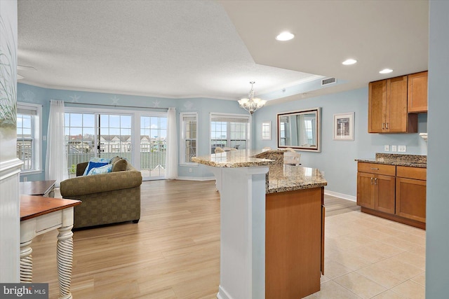 18 79th St Unit 403, Ocean City, MD 21842 - kitchen with a chandelier, a breakfast bar area, light stone counters, brown cabinetry, and recessed lighting