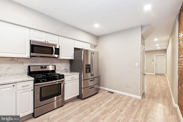 2012 Eagle St, Baltimore, MD 21223 - kitchen with light wood-style floors, white cabinets, tasteful backsplash, and stainless steel appliances