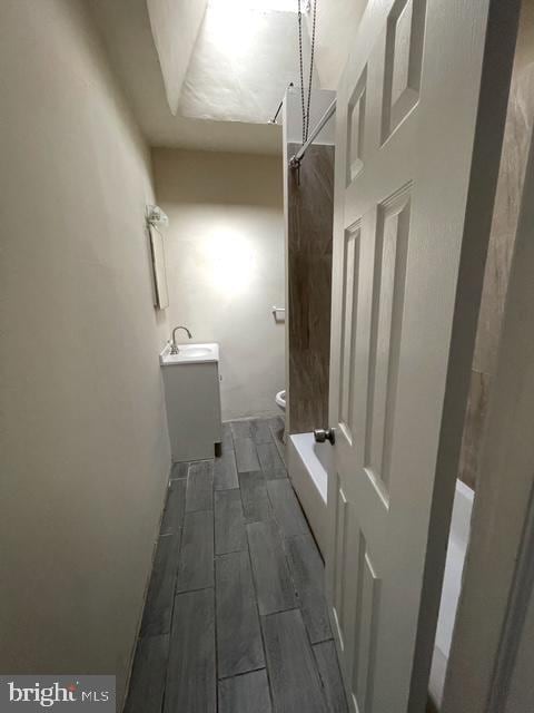bathroom with toilet, wood finish floors, a shower, and vanity