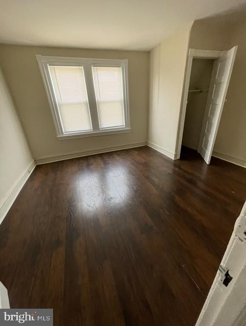 unfurnished bedroom with baseboards, a closet, and dark wood finished floors