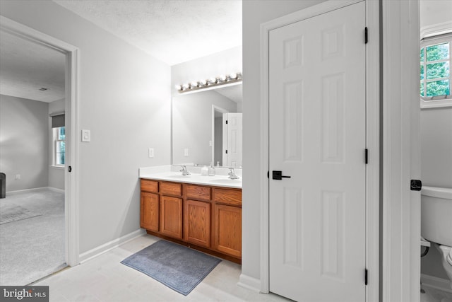 full bathroom featuring double vanity, toilet, and baseboards
