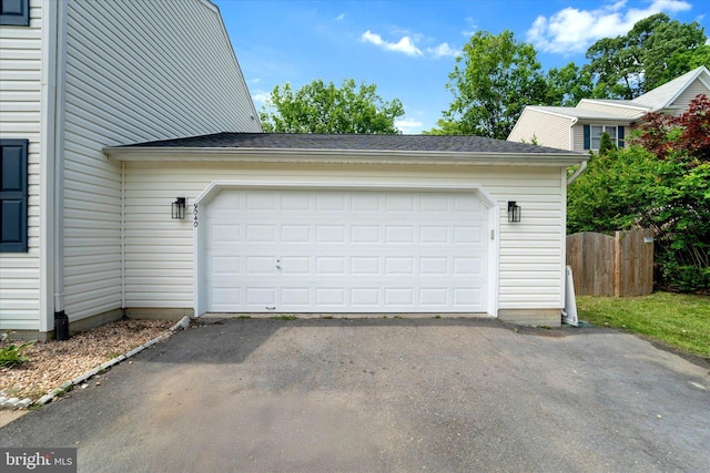 garage with asphalt driveway and fence