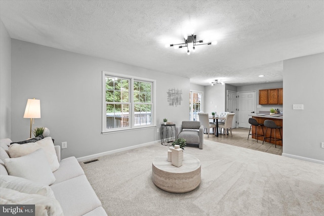 living room with baseboards, a textured ceiling, light carpet, and a chandelier