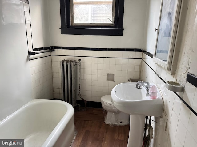 531 N 63rd St, Philadelphia, PA 19151 - bathroom featuring wainscoting, radiator, a tub, tile walls, and wood finished floors