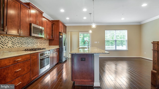 kitchen with appliances with stainless steel finishes, crown molding, light stone countertops, a center island with sink, and tasteful backsplash