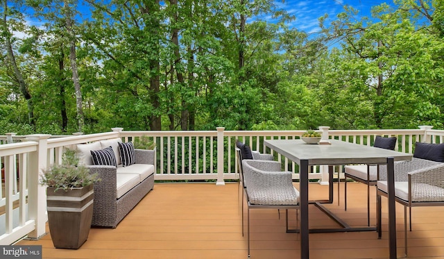 wooden terrace with outdoor dining area and view of wooded area