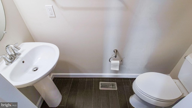 bathroom with baseboards, toilet, and a sink