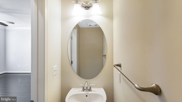 bathroom featuring a sink, ornamental molding, wood finished floors, and a ceiling fan