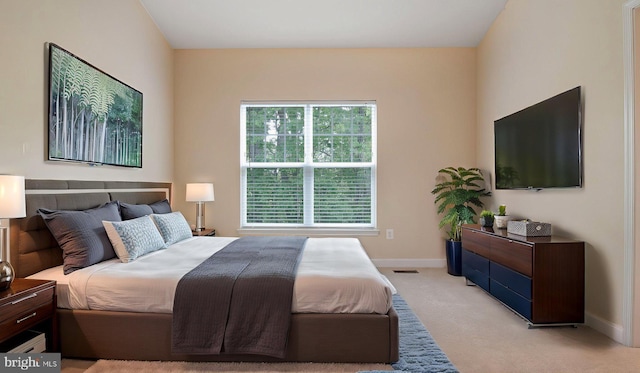 bedroom with light colored carpet and baseboards