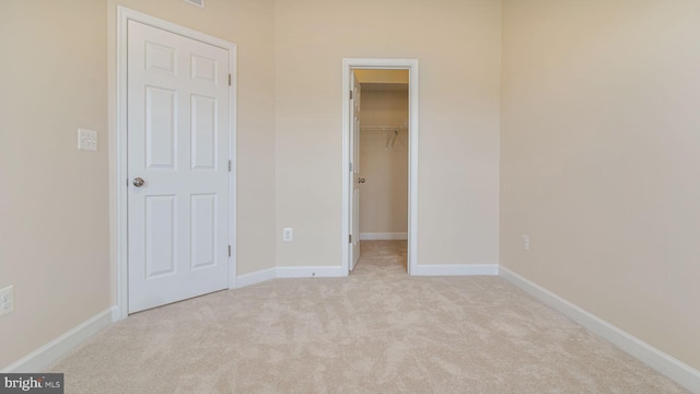 unfurnished bedroom featuring carpet floors, a spacious closet, baseboards, and a closet