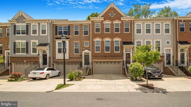 townhome / multi-family property featuring concrete driveway, a garage, brick siding, and stairs