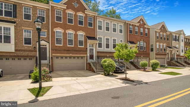 multi unit property featuring brick siding, a residential view, an attached garage, and driveway